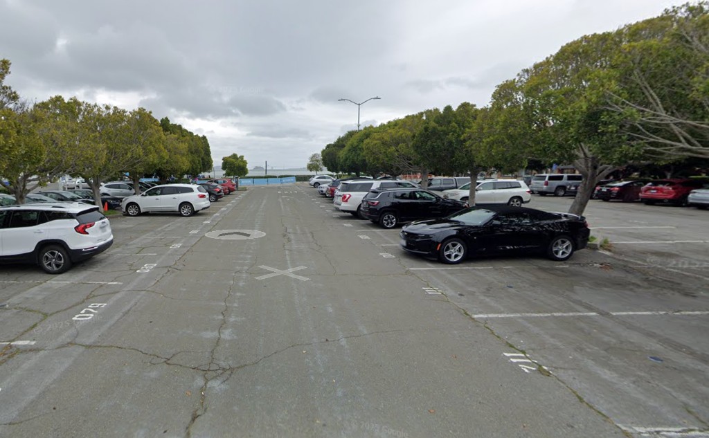 A nearly empty Sausalito waterfront parking lot with a few cars under trees